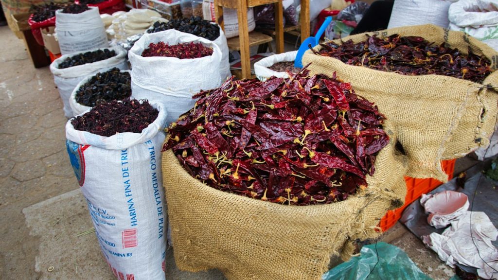 Dried Indian chillies of differing colour in burlap sacks